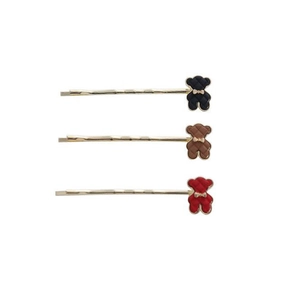 Détail de trois jolies barrettes d'ours en noir, marron et rouge avec des nœuds dorés