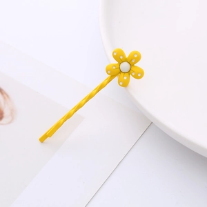 Détail d'une barrette à fleurs jaunes à pois blancs sur une assiette blanche épurée