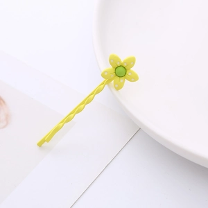Détail d'une pince à cheveux fleur jaune à pois blancs sur une assiette en céramique