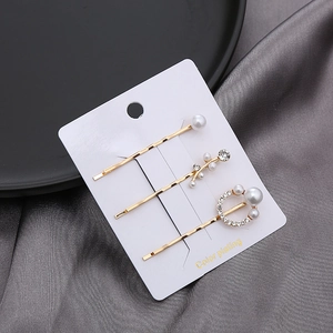 Dreiteiliges elegantes goldenes Haarspangen-Set mit Perlen und Strass auf weißer Karte