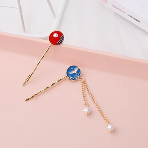 Close-up of golden tassel hair clips with red and blue enamel crane patterns and pearls