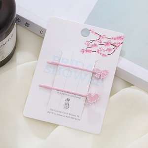 Set di fermagli rosa con fiocco, cuore e perle su base di cartoncino