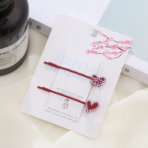 Fermagli per capelli giapponesi rossi con fiocco, cuore e perle su carta regalo