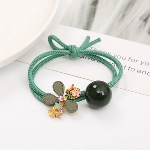 Détail du pendentif fleur de camélia et chouchou élastique vert orné d'une perle fine