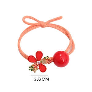 Détail d'un chouchou orange avec une fleur de camélia rouge de 2,8 cm et une perle rouge