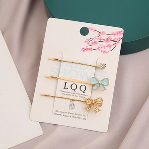 Lot de 3 barrettes dorées avec nœud en émail bleu et strass sur carte de présentation