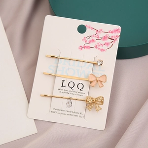 Détail du lot de 3 pinces à cheveux dorées avec nœuds en émail rose et strass brillants