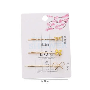 Détail d'un lot de trois barrettes dorées avec nœuds en émail jaune et champagne