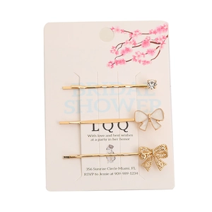 Lot de barrettes dorées géométriques avec nœud blanc et strass sur carte florale