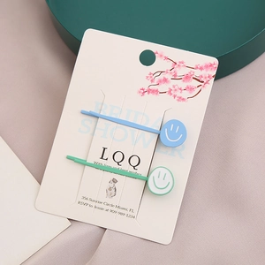 Détail de barrettes smiley bleues et vertes sur carte d'affichage fleurs de cerisier