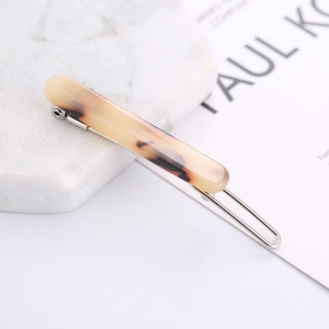 Elegant tortoiseshell acetate hair clip with silver alloy clip on white marble background