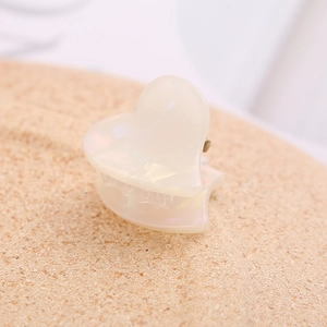Close-up of small heart claw clip in pearlescent cream acetate with gold metal spring