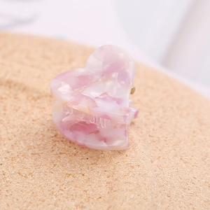 Close-up of pink and white marble textured acetate heart-shaped hair claw clip accessory