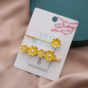Ensemble de deux barrettes marguerites en alliage doré et émail jaune sur satin