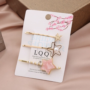 Elegant gold hair clip set with pink stars and white pearls on soft pink satin background