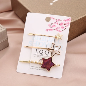 Detail view of 3-piece star hair clip set featuring gold finish, pearls and purple texture