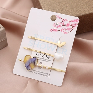 Detailed view of heart-shaped hair clips set with pearls and rhinestones on card