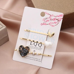 Detail of three heart hair clips with pearls and tortoise texture on a gift box