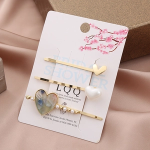 Three-piece gold heart hair clip set with marble resin and pearl on display card