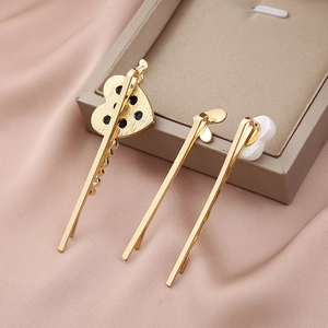 Detail view of gold heart hairpins with rhinestones and pearls on silk fabric background