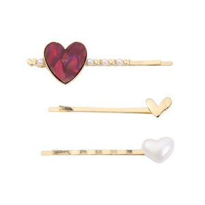 Detailed view of three-piece heart-shaped gold hair clips with pearls and marble textures