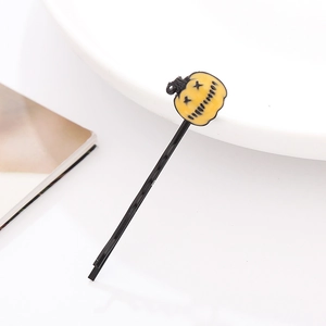 Detail of a black metal hair clip featuring a glossy yellow Halloween pumpkin charm