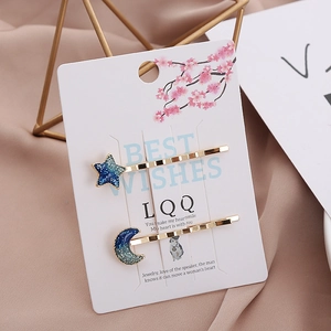 Macro detail of blue starry night cat hair pins with gold metal moon and star charms