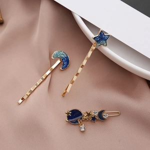 Close-up of three celestial hairpins with blue glitter enamel and rhinestones on satin