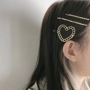 Detailed view of three-piece gold metal hair clips with pearls on a model side profile