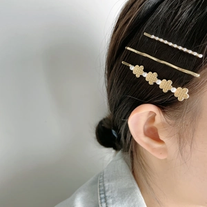 Close-up of three-piece gold metal hair clips with pearls on elegant black hair