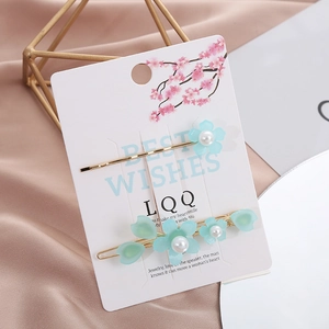 Dettaglio di fermagli per capelli con fiori azzurri e perle su sfondo di seta rosa