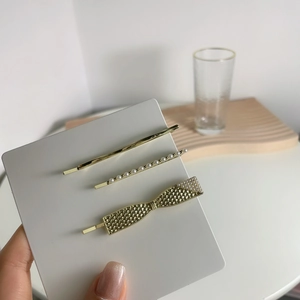 Three-piece gold hair clip set with pearls and minimalist metal designs on a display card