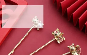 Detail van matte gouden tijger haarspelden met parels en Chinese gelukstekens op de clip