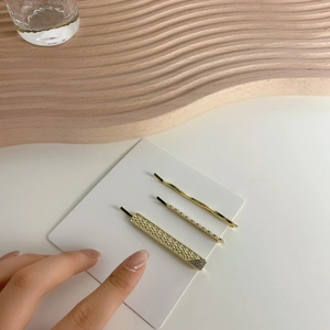Three-piece gold hair clip set with smooth metal, pearls, and glitter on white display card