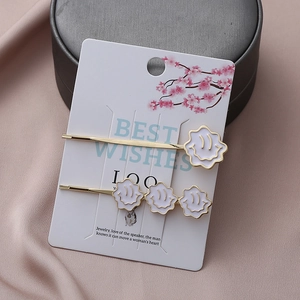 Ensemble de barrettes dorées avec fleurs en émail blanc sur carte de vœux
