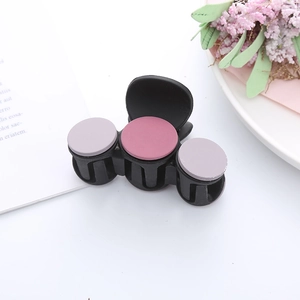 Detailed top view of a matte black hair claw clip with colorful pastel accents on a table
