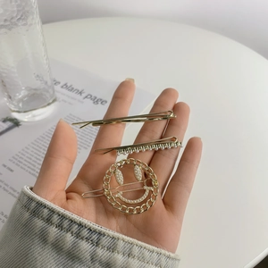 Detailed view of 3-piece gold hair clip set with smiley face and pearl accents