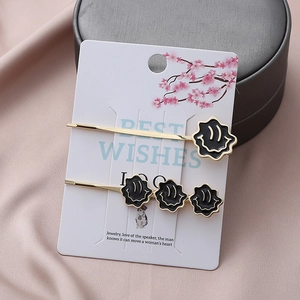 Barrettes dorées avec pendentifs souriants noirs sur emballage carte fleur de cerisier