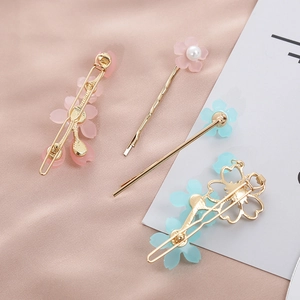 Dettaglio di fermagli per capelli con fiori di ciliegio in resina e perle su seta rosa