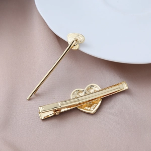 Detail of gold metal heart-shaped hair clips on elegant purple silk fabric background