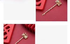 Detail van matgouden haarclip met een 3D-gelukstijger op een rode waaier achtergrond