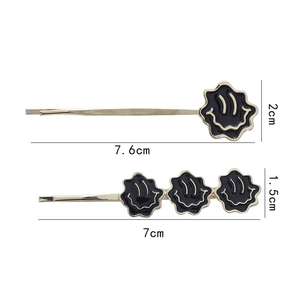 Détail montrant les dimensions des barrettes fleurs sourire noires sur tiges dorées