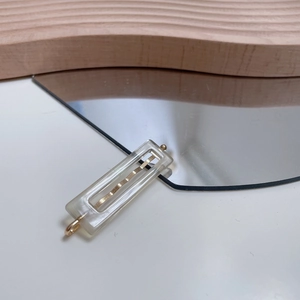 Minimalistische Haarspange aus bernsteinfarbenem Acetat auf Holzdekor im Rechteckdesign