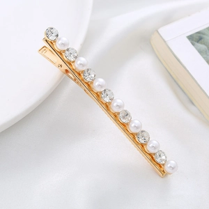 Detailed view of elegant gold hair clip with pearls and crystals on silk fabric