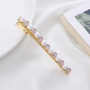 Detail of elegant gold hair clip with alternating pearls and pink crystals on white silk