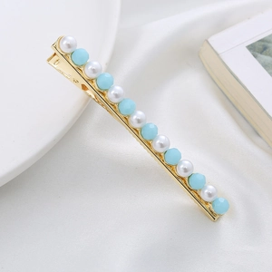 Detail of elegant gold hairpin featuring white pearls and light blue crystal beads