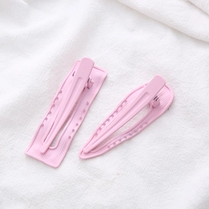 Detail of pink matte duckbill hair clips with non-slip teeth on white textured fabric