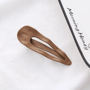 Detailed view of a matte coffee brown wavy teardrop hair clip on a textured fabric