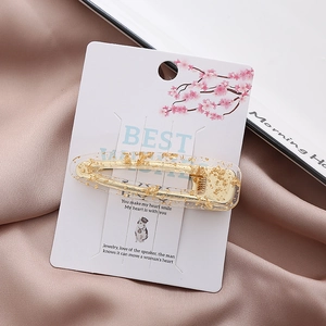 Detail of transparent resin hair clip with gold foil flakes on a decorative display card