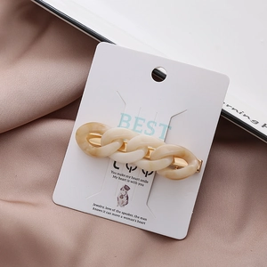 Eleganter Acryl-Haarclip mit Gliederketten-Design auf rosa Seidenhintergrund